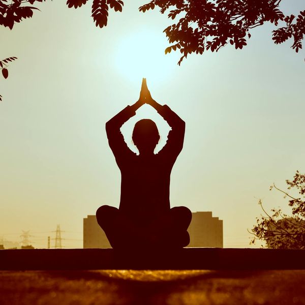 Silhouette of a person meditating against a sunrise.